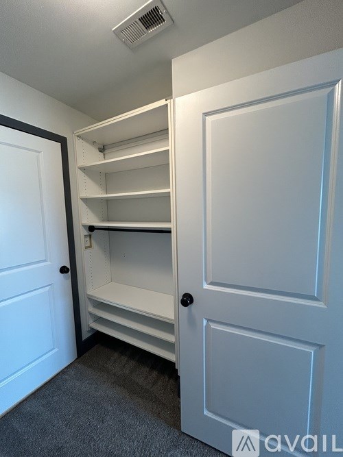 A white door with a black handle is open to a white closet with shelves.