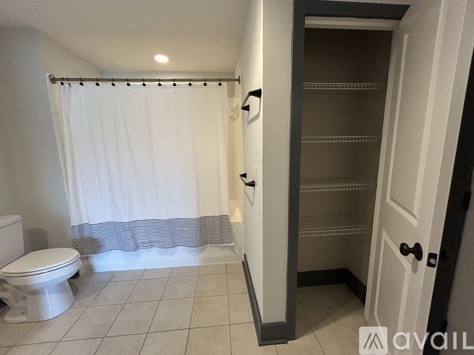 A bathroom with a toilet, shower curtain, and a door.