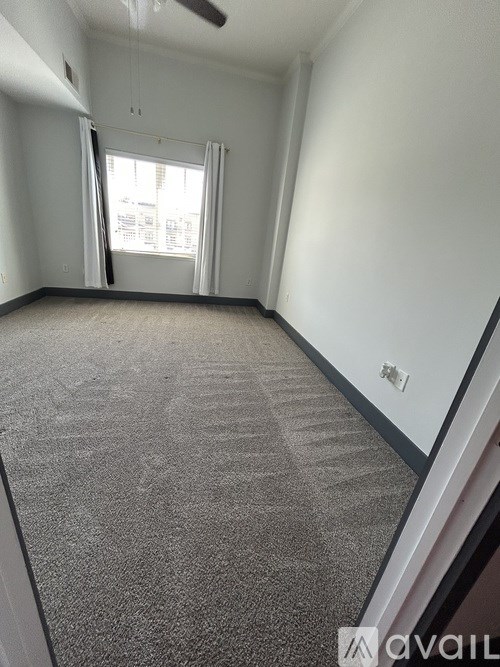 A room with a carpeted floor and a window with curtains.