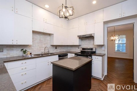 A modern kitchen with white cabinets and a black island.
