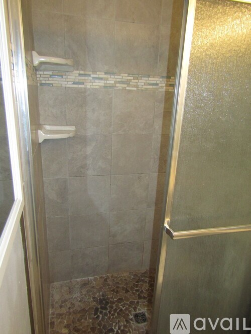 A shower area with a glass door and tiled walls.