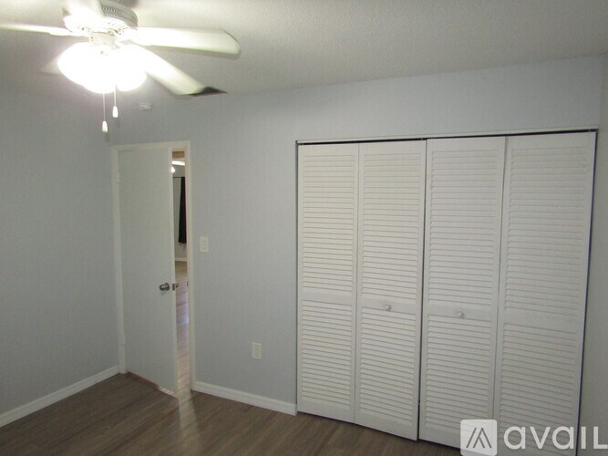 A room with a ceiling fan and three closets.
