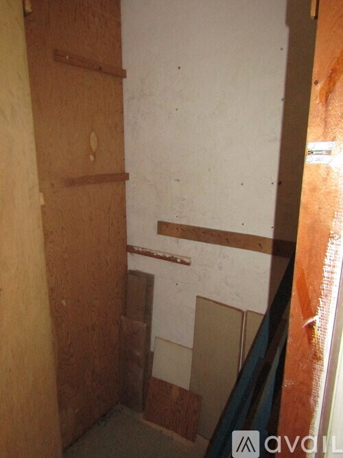 A room with a white wall and a brown door.