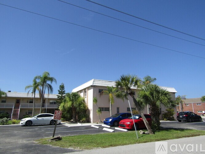 A white car is parked in front of a building with a no parking sign.