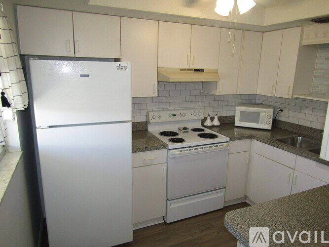 A kitchen with white appliances and cabinets.