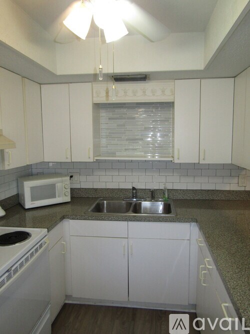 A kitchen with white cabinets and a stove top oven.