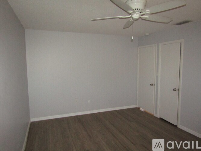 A room with a ceiling fan and two doors.