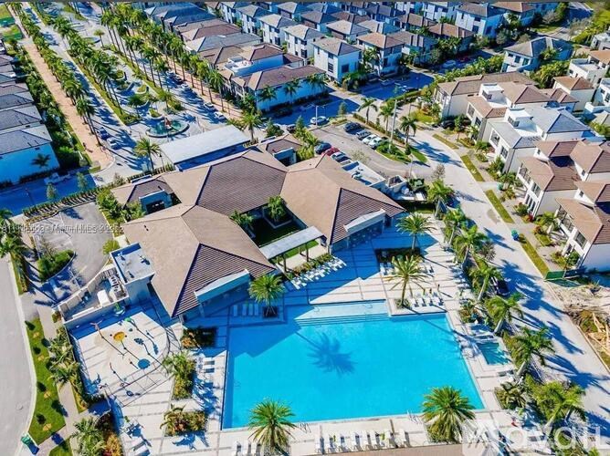 A large house with a pool in the foreground and smaller houses in the background.