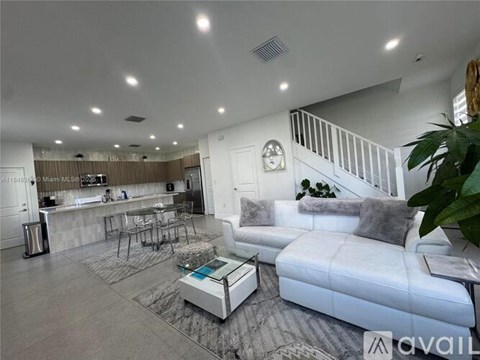 A modern living room with a white sofa and a wooden bar area.
