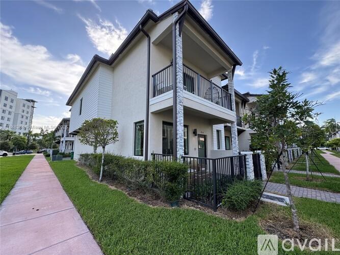 A white two-story house with a balcony on the second floor.