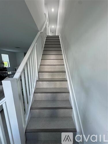 A staircase with a white railing and beige carpeted steps.