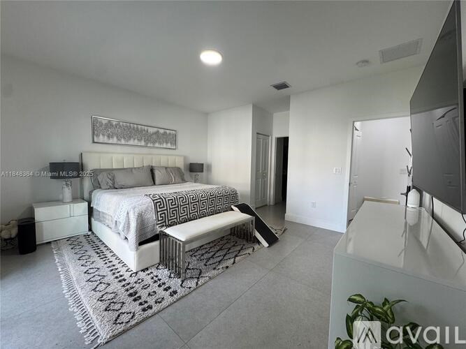A bedroom with a large bed and a bench in the middle of the room.