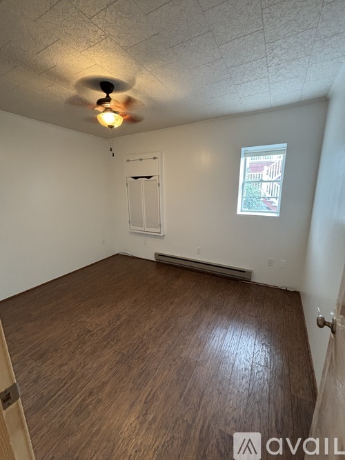 A room with a ceiling fan and a window with a view of a building.