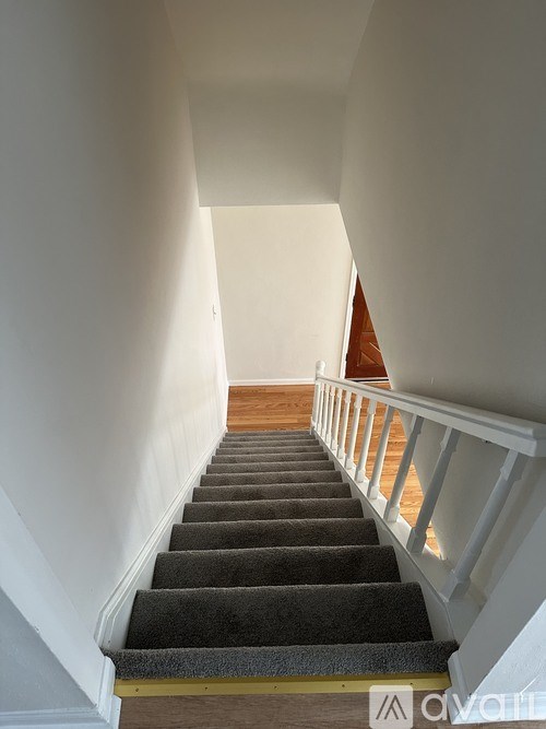 A staircase with a carpeted runner and white railings.