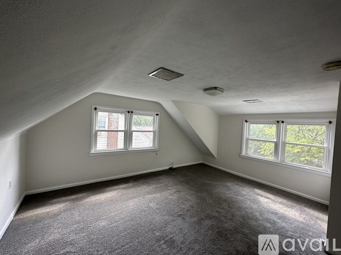 A room with a carpeted floor and two windows.