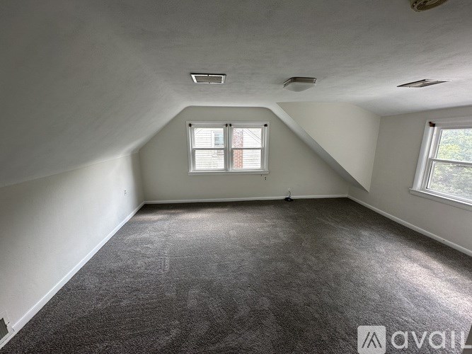 A room with a carpeted floor and two windows.
