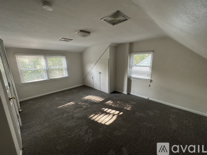 A room with a carpeted floor and a window with blinds.