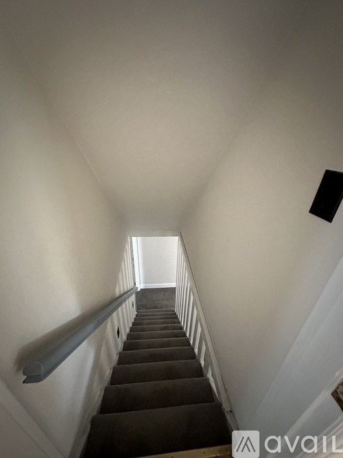 A staircase with a black railing leading to a white door.