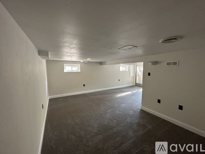 A spacious empty room with a window and a ceiling light.