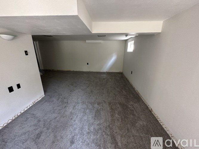 A room with a grey carpet and white walls is available for rent.