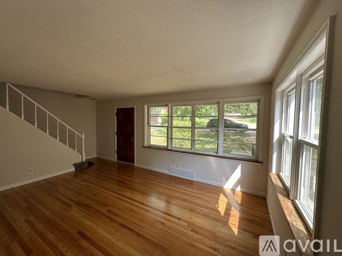 A room with wooden floors and a staircase leading to another floor.