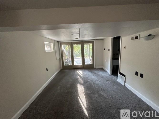 A spacious room with a carpeted floor and a door leading to a balcony.