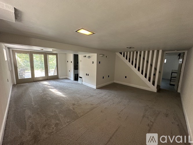 A spacious room with a staircase and a large window.