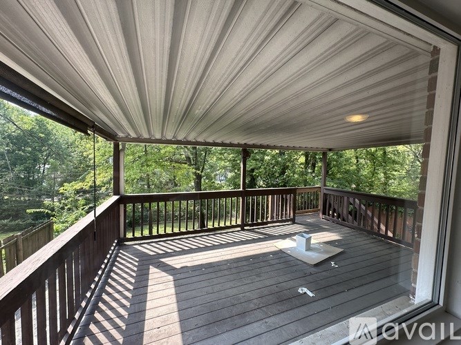 A wooden deck with a white ceiling and a view of trees.