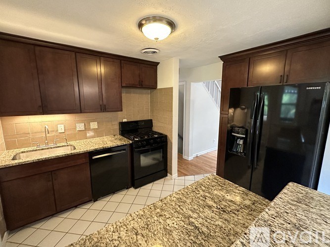 A kitchen with black appliances and brown cabinets.