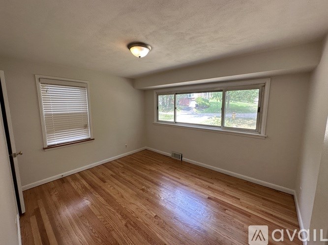 A room with wooden flooring and a window with blinds.