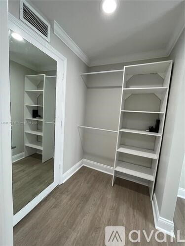 A white closet with shelves and a mirror.