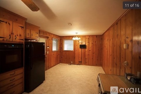 A kitchen with wooden cabinets and a black refrigerator.