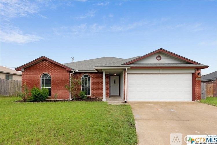 A red brick house with a white garage door and a grey roof.