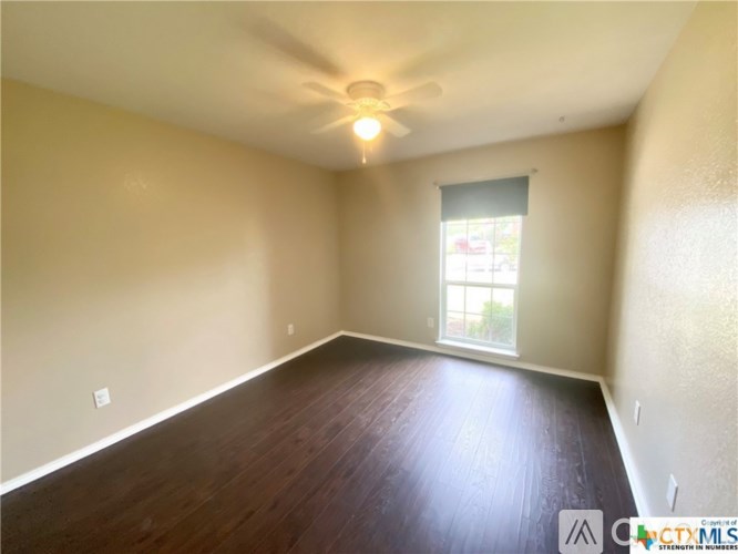 Empty room with wooden floor and ceiling fan.