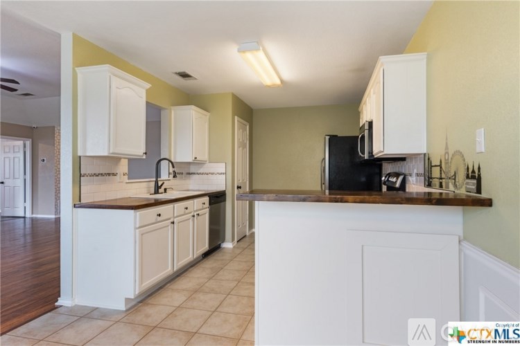 A kitchen with white cabinets and a black fridge.