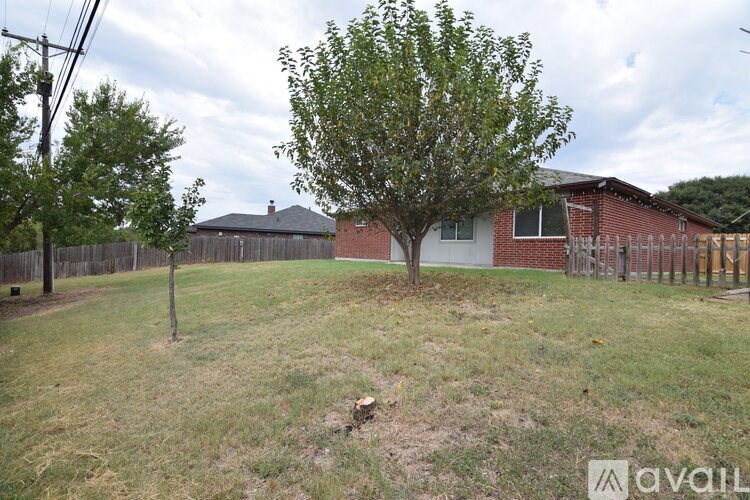 A tree in a yard with a house in the background.