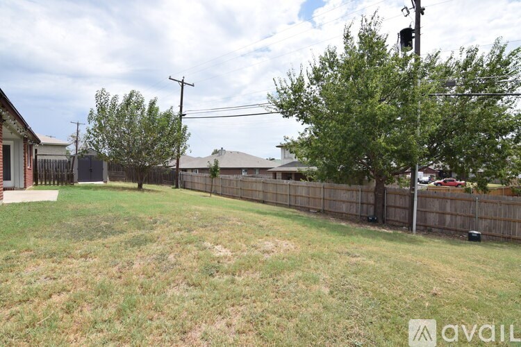 A grassy area with a fence and trees in the background.