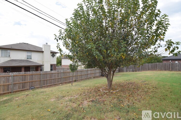 A tree in a yard with a house in the background.