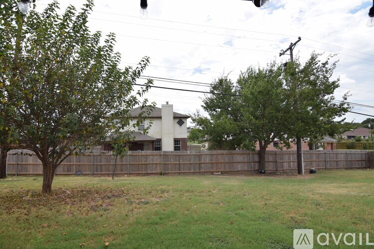 A house with a fence and trees in front of it.