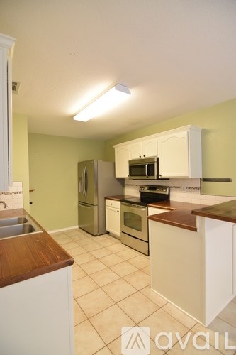 A kitchen with white cabinets and a black refrigerator.