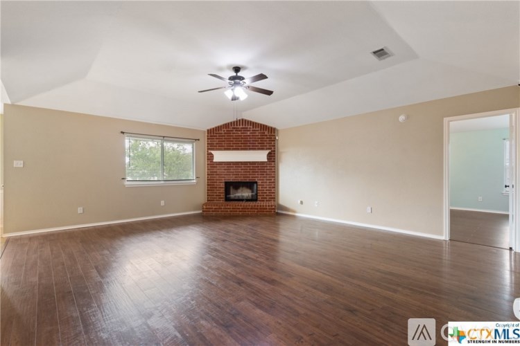 A spacious room with a fireplace and a ceiling fan.