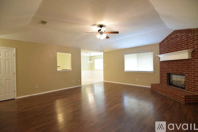 A room with a brick fireplace and wooden floors.