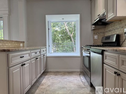 A kitchen with white cabinets and a window.
