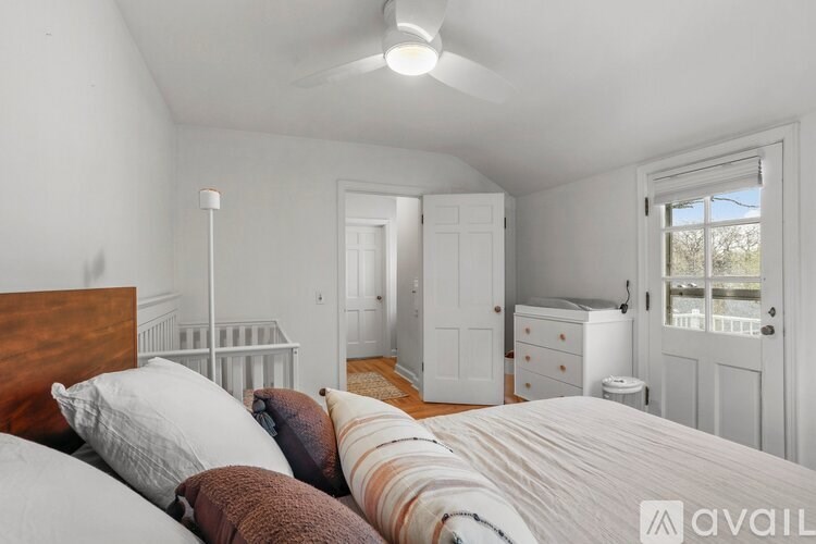 A bedroom with a bed, pillows, and a window.
