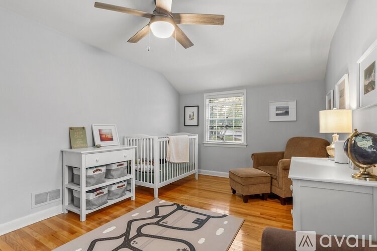 A baby nursery with a crib, changing table, and a rocking chair.