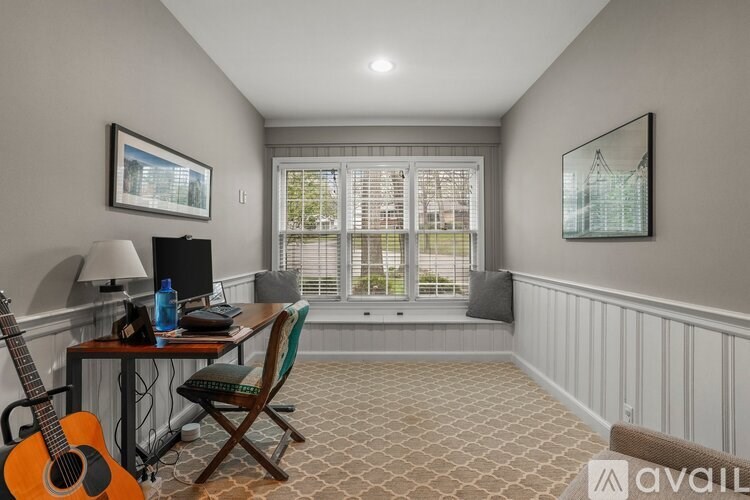A room with a desk, chair, and guitar.