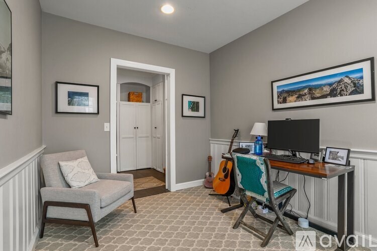 A room with a chair, a desk, and a guitar.