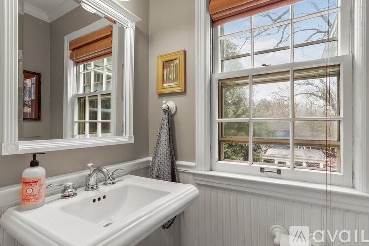A bathroom with a white sink and a window with a view of a tree.