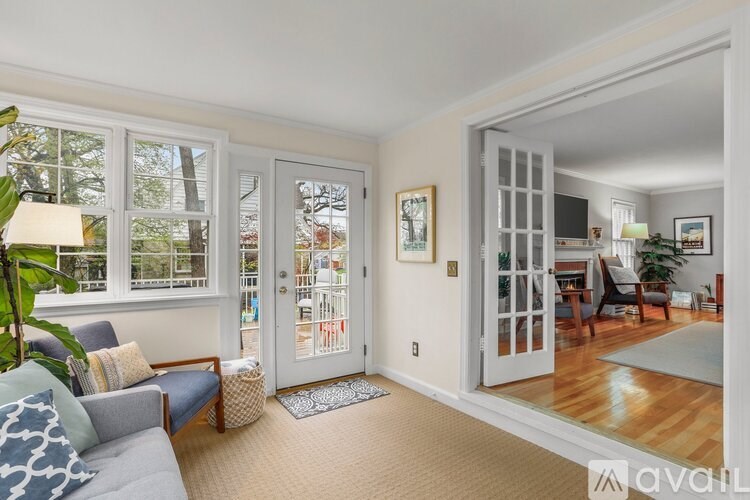 A living room with a couch, a chair, a table, a potted plant, and a mirror.