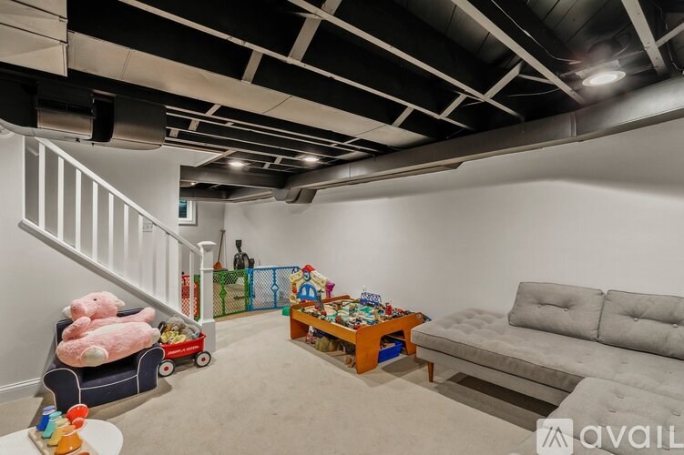 A living room with a grey sofa, a coffee table, a toy truck, and a playpen.